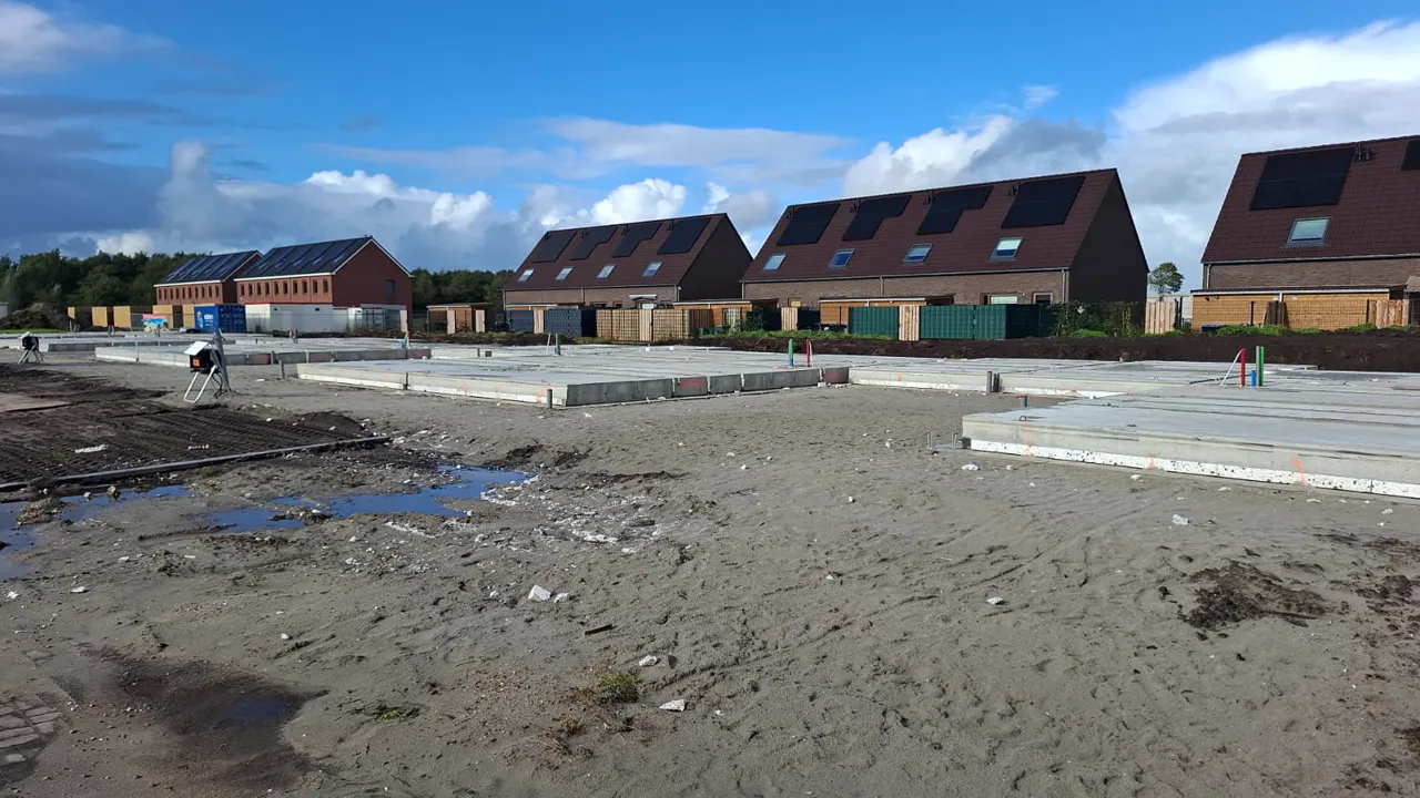 Vloerplaten op het bouwterrein met woningen in de omgeving op de achtergrond