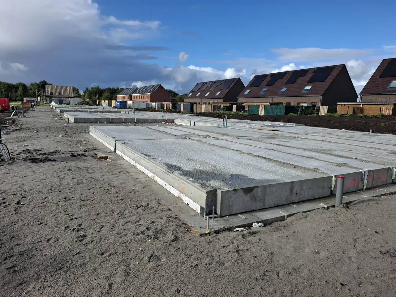 Betonnen vloerplaten op het bouwterrein in Wyldehoarne met woningen in de omgeving op de achtergrond